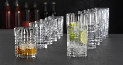 NACHTMANN Des gobelets Highland Square et des verres à long drink alignés les uns derrière les autres. Le gobelet de devant est rempli de Whiskey on the rocks et le verre à long drink de devant est rempli d'une boisson claire avec des tranches de citron vert et des glaçons.<br/>