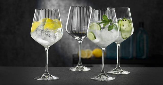 Four NACHTMANN Gin and Tonic glasses, three of them filled with different gin cocktails, one of them empty.<br/>