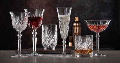 La série Palais de NACHTMANN avec le gobelet à vin blanc à côté du gobelet à vin rouge rempli, le verre à champagne conique rempli, le verre à whisky rempli, le verre à cocktail rempli et le verre à jus de fruits.<br/>
