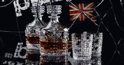 La carafe NACHTMANN Punk remplie de whisky et deux gobelets à whisky Punk sont posés sur une table noire devant un miroir brisé avec le mot punk écrit et un junion jack dans ce miroir.<br/>
