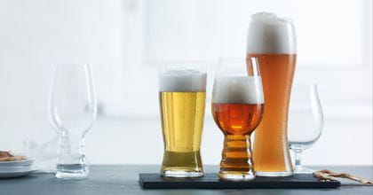 The Spiegelau Craft Beer IPA glass is positioned on the left of the image unfilled with the Spiegelau Beer Classics Tasting Set positioned on the right side of the image filled with their style-specific beer.