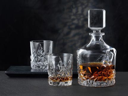 La carafe à whisky NACHTMANN Sculpture et le gobelet à whisky NACHTMANN Sculpture, tous deux remplis de whisky. À l'arrière-plan, un gobelet Sculpture vide sur un plateau de service.<br/>