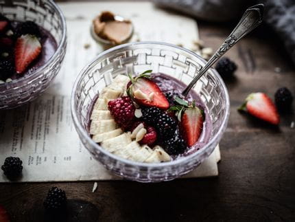 Le bol alimentaire Bossa Nova de NACHTMANN est rempli d'un smoothie à la crème violette surmonté d'une garniture de fruits composée d'une banane coupée en tranches, de mûres et d'une fraise coupée en deux.<br/>