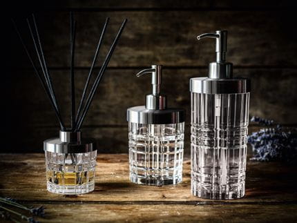 La série Spa Square de NACHTMANN sur un buffet en bois. Le diffuseur de parfum est rempli d'une fragrance et de huit bâtonnets noirs. À droite, le petit et le grand distributeur de savon.<br/>