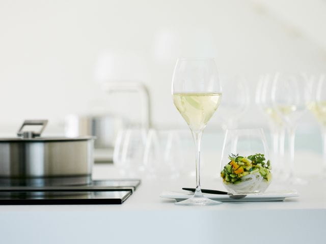 The with white wine filled SPIEGELAU Adina Prestige white wine glass besides a SPIEGELAU Authentis Casual tumbler filled with a veggie noodle salad.<br/>