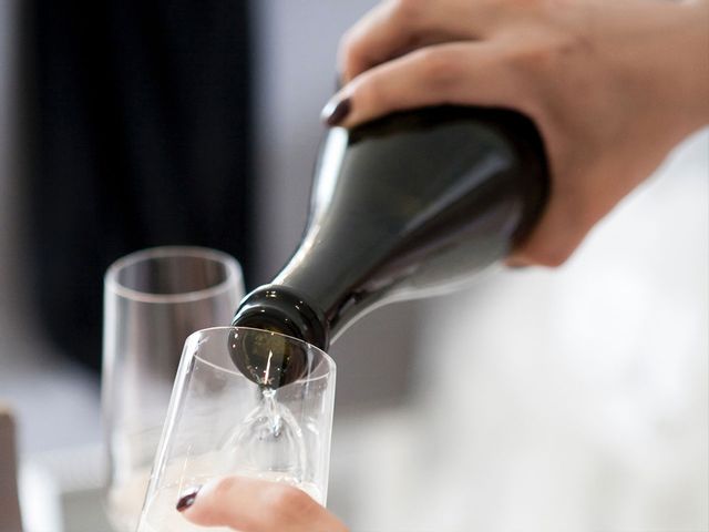A hand pouring Champagne into a Champagne glass.