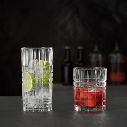 Le verre à long drink NACHTMANN Highland Square rempli d'une boisson claire avec du citron vert et des glaçons et le gobelet rempli d'une boisson Campari on the rocks.<br/>
