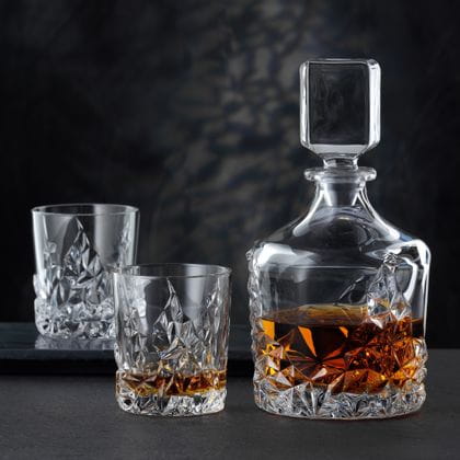 La carafe à whisky NACHTMANN Sculpture et le gobelet à whisky NACHTMANN Sculpture, tous deux remplis de whisky. À l'arrière-plan, un gobelet Sculpture vide sur un plateau de service.<br/>