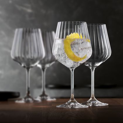 Deux verres à pied NACHTMANN Masterpiece, l'un est rempli d'un Gin and Tonic et d'un zeste de citron, l'autre est vide. À l'arrière-plan se trouvent deux autres verres Masterpiece vides.<br/>