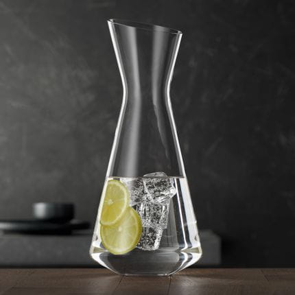 The slim SPIEGELAU Style decanter filled with water, lemon slices and ice cubes on a wooden table.<br/>