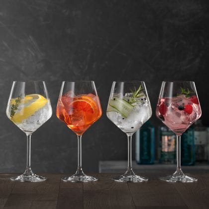 Quatre verres à Gin et Tonic SPIEGELAU posés sur une table en bois, chacun rempli d'un cocktail Gin différent.<br/>